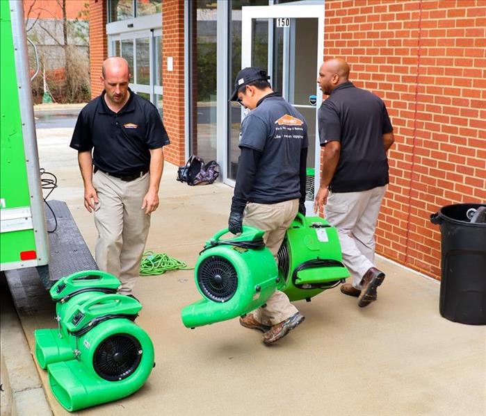 3 SERVPRO technicians carrying air movers for water damage drying